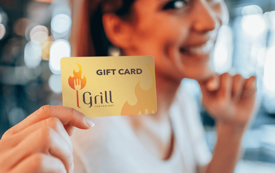 A woman holding up a gift card in front of her face.