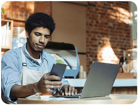A man sitting at a table using his phone.