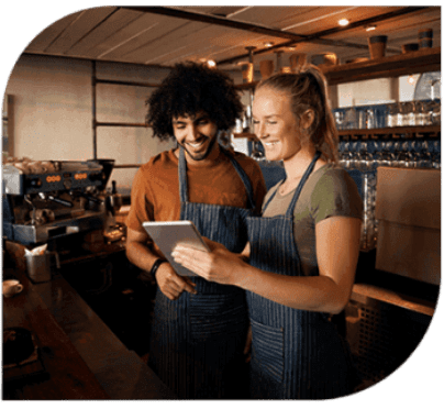 Two people in aprons looking at a tablet.