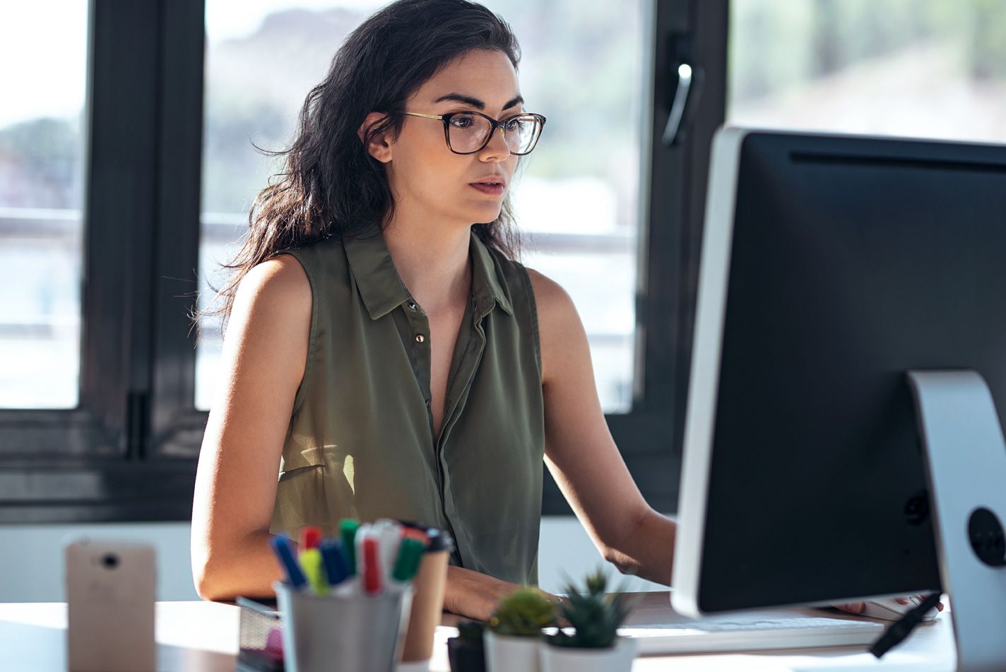 A woman sitting at her desk looking at the computer screen.