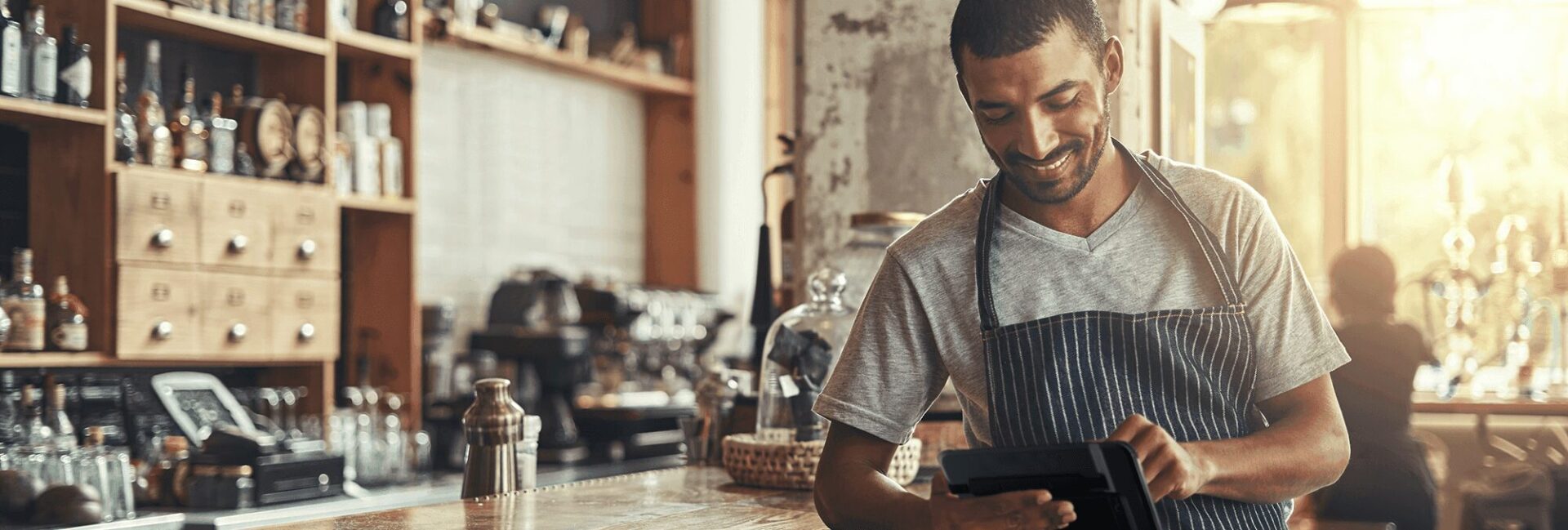 A man in an apron is looking at his tablet.