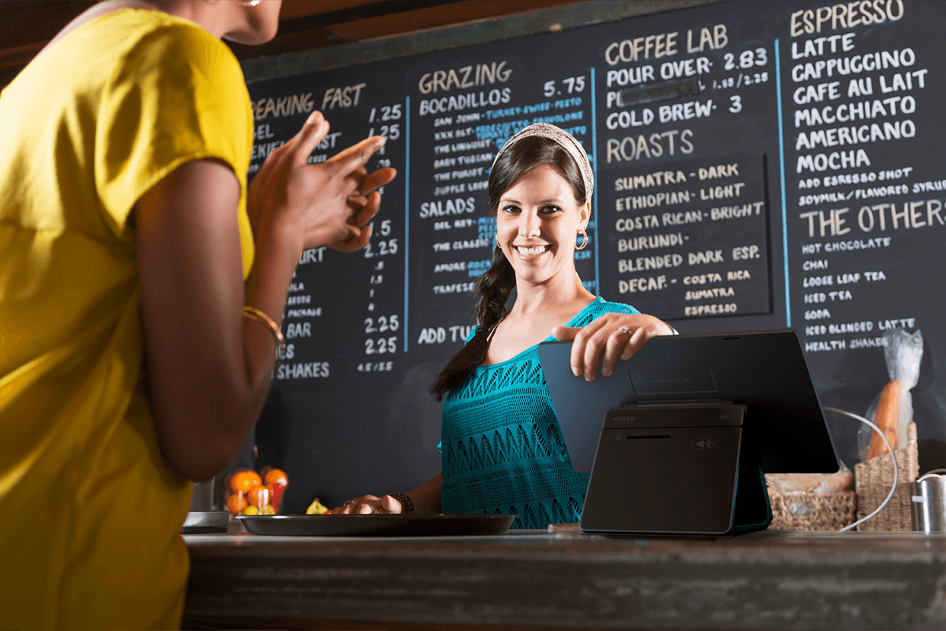 Barista smiling at customer in coffee shop.