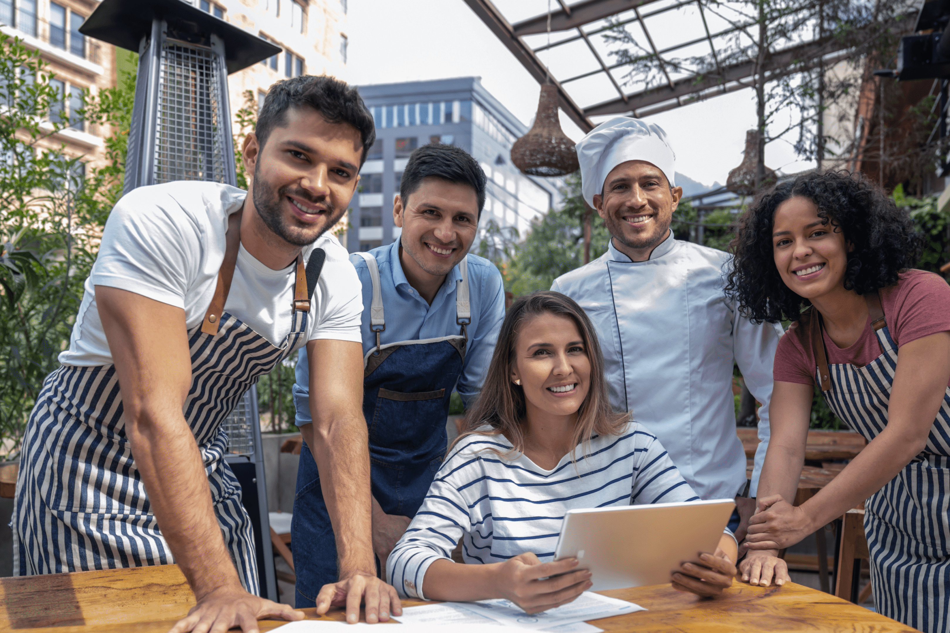 Group of smiling restaurant staff outdoors.