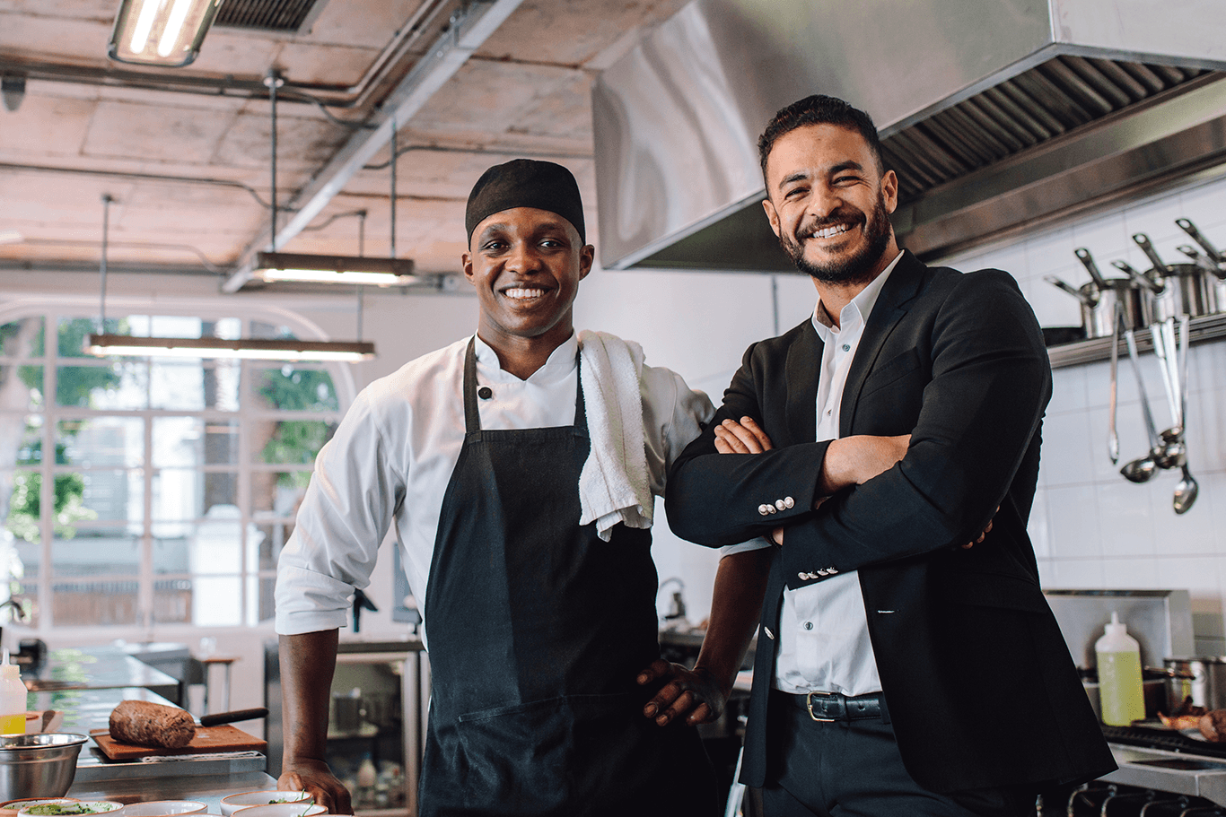 Chef and businessman smiling in kitchen.