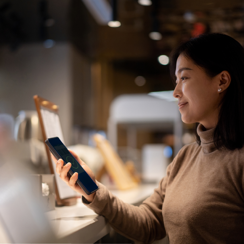 Woman using smartphone in a cozy cafe.