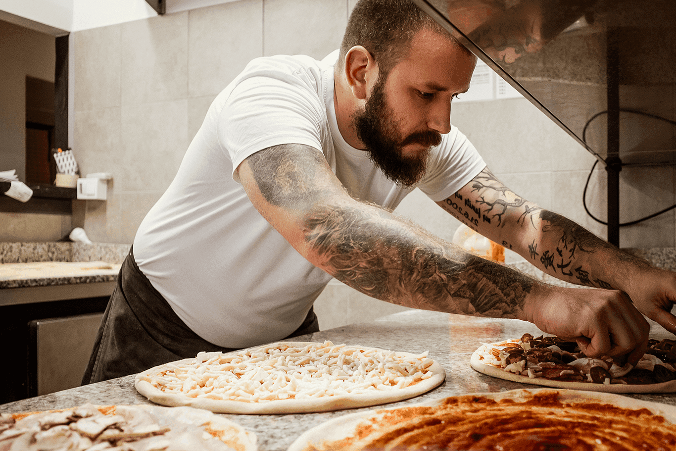 Chef preparing pizzas in a kitchen.
