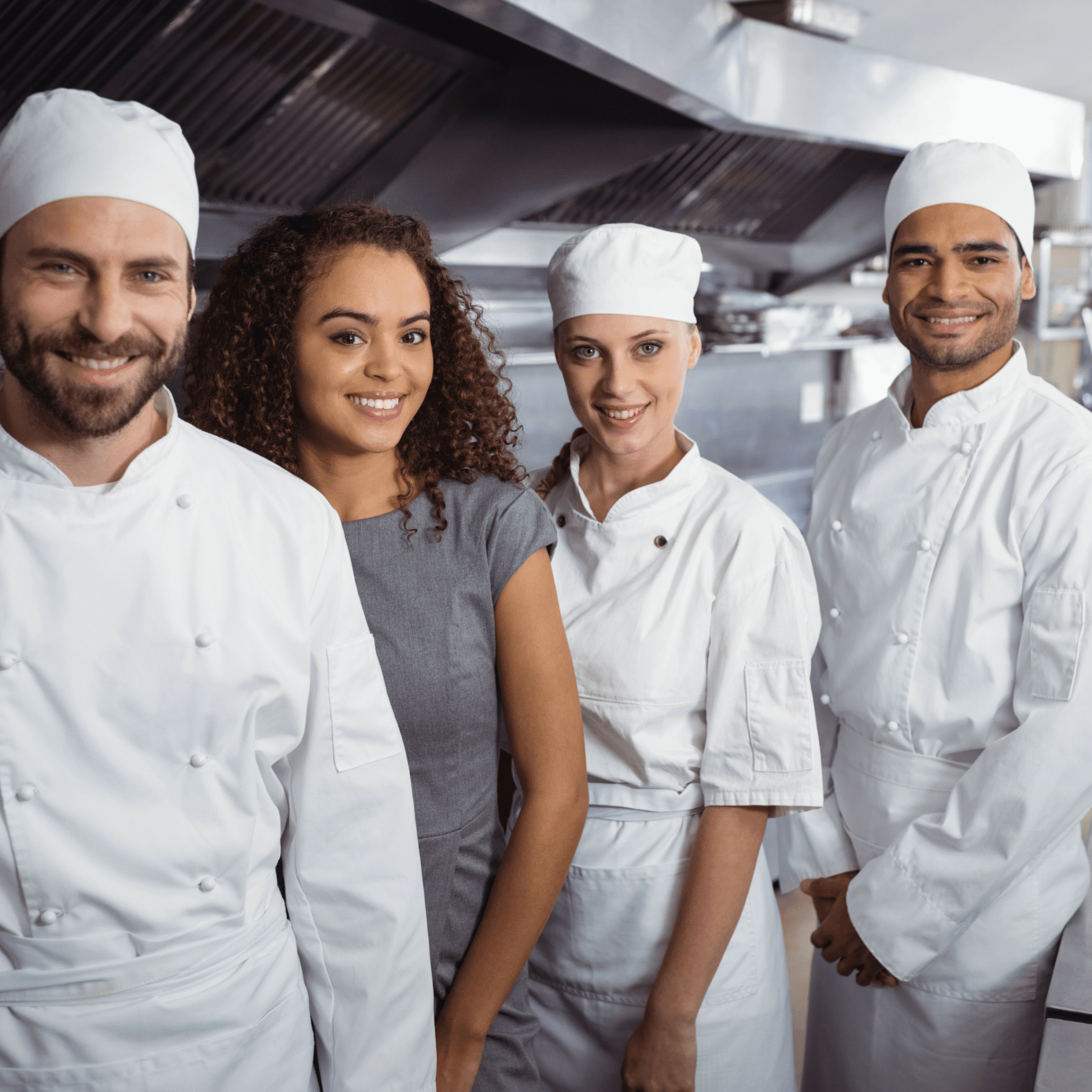 Chefs and manager smiling in restaurant kitchen.